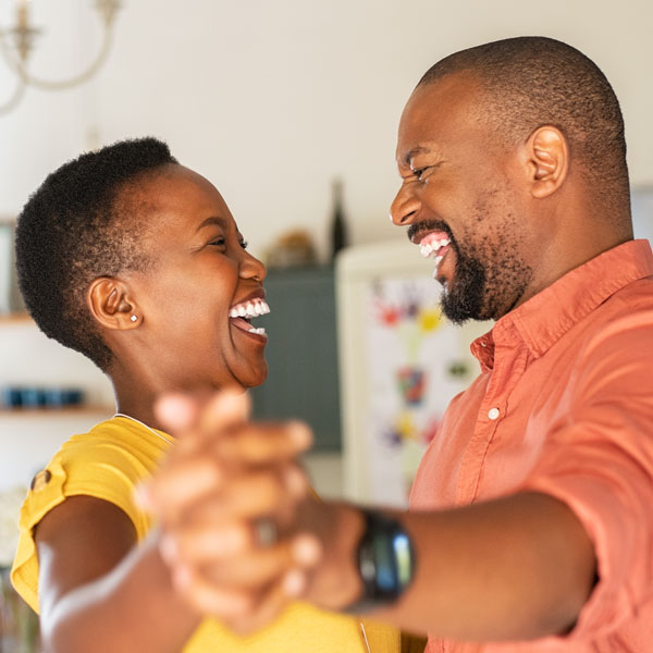 Happy adult couple dancing in the kitchen after a successful cosmetic dental treatment in Wyoming