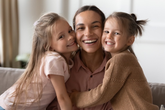 Mother smiling with family after getting cosmetic bonding for front teeth in Wyoming, MI